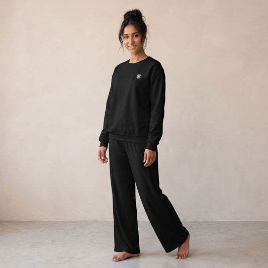 Model wearing a black sweatshirt with small pearl shell embroidery on the chest and matching black wide-leg pants.