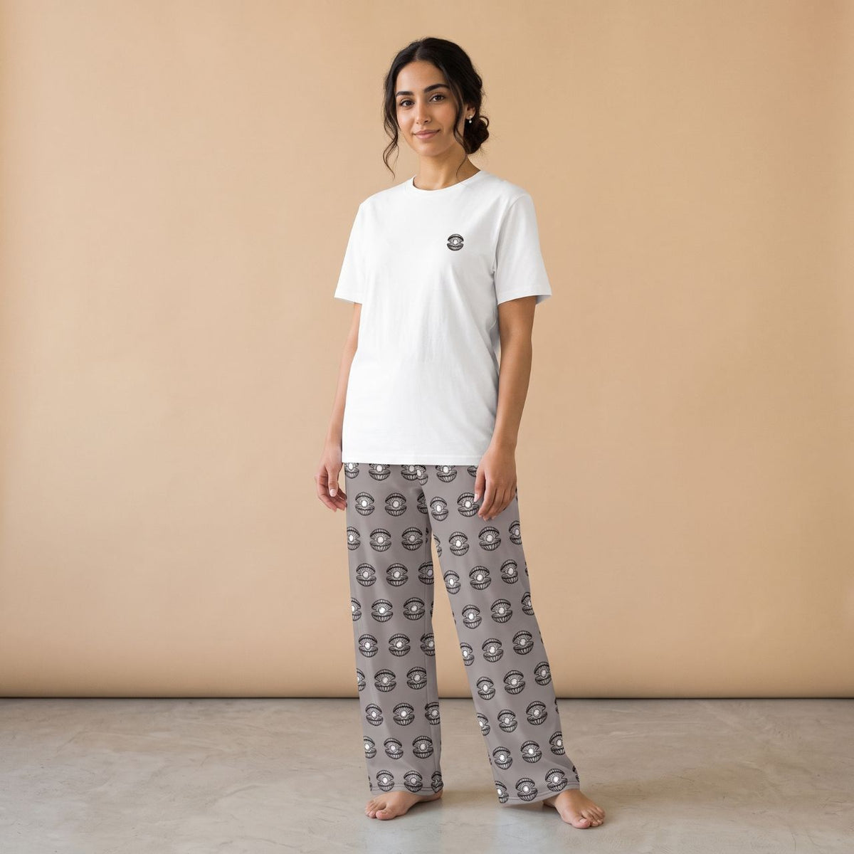 Model wearing a white T-shirt with a small pearl shell motif and grey pants with matching pearl shell prints, front view.
