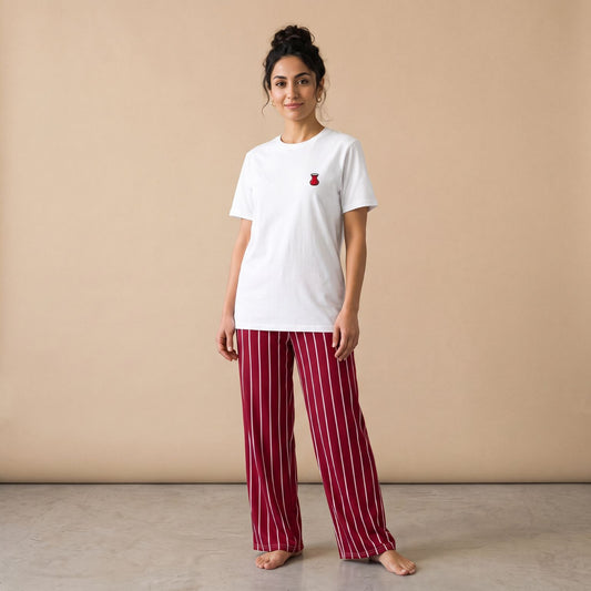 Model wearing a white T-shirt with a small red tea glass motif and dark red pants with white vertical stripes, front view.