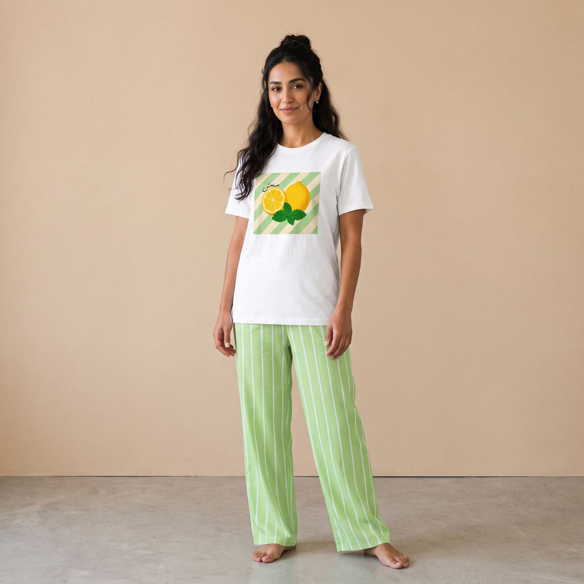 Model wearing a white lemon-and-mint graphic T-shirt and light green pants with white vertical stripes, front view.