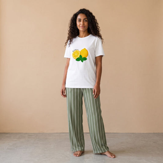 Model wearing a white lemon-and-mint graphic T-shirt and sage green pants with white vertical stripes, front view.