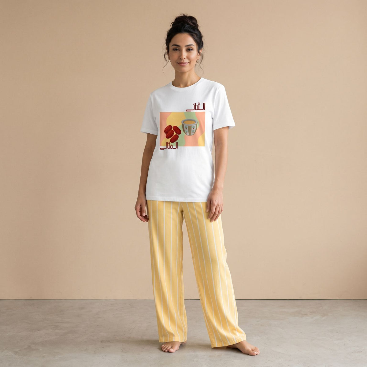 Model wearing a white coffee-and-dates graphic T-shirt and pale yellow pants with white vertical stripes, front view.