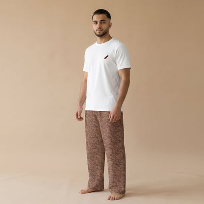 Male model wearing a white T-shirt with a small tikka skewer graphic and chocolate-brown pants with an all-over food print.