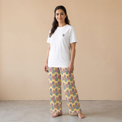 Model wearing a white T-shirt with a small virtual pet motif and pale yellow pants with colourful virtual pet prints, front view.