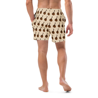 A man wearing beige swim trunks with a repeating brown guitar pattern, shown from the back against a plain white background.