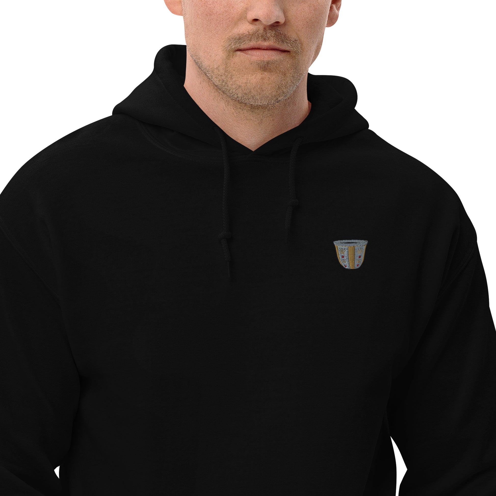 A man wearing a black pullover hoodie with a small finjan embroidered design on the left chest, shown against a plain white background.